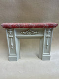 A white 1:12 miniature scale decorative fireplace mantel, featuring a pink marble-look top by artisan Jim Coates