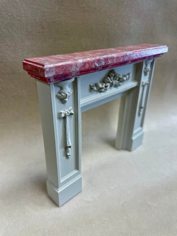 A 1:12 miniature scale fireplace with faux pink marble mantle created by artisan Jim Coates, 