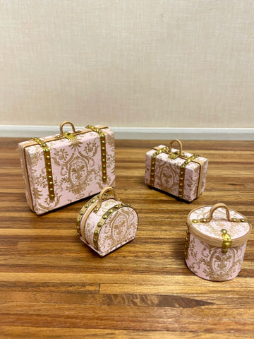 Four 1"12 miniature scale travel cases in a light pink damask pattern with gold-tone hardware