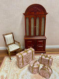 A set of miniature pink damask-patterned dollhouse suitcases 
