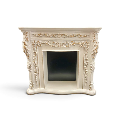 An ornate miniature cream-colored fireplace mantel with intricately carved gold painted details.