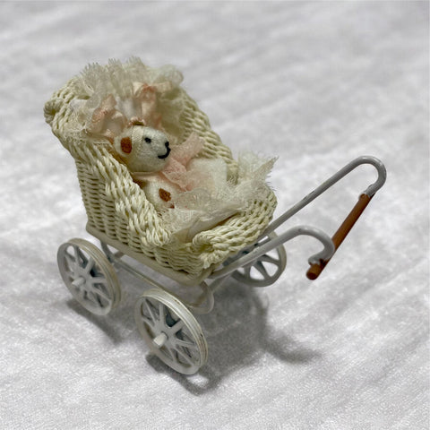 Dollhouse Miniature pram with a knitted teddy bear inside.